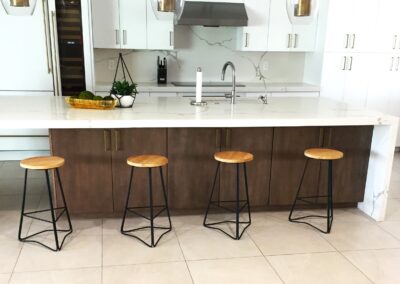 A modern kitchen with wooden stools and a white island.